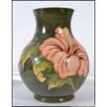 A large Walter Moorcroft pattern tubeline decorated vase on green ground with pink flowers,