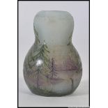 A stunning miniature enamelled glass vase being hand painted with furn trees and lake scene being