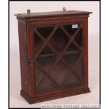 An early 20th century oak wall cabinet having single astragal glazed door front