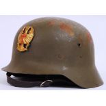 A SPANISH CIVIL WAR (M-42) STEEL HELMET bearing a Civil War brass helmet badge to front,