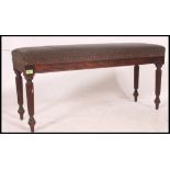 A Victorian style mahogany duet piano window stool seat with overstuffed seat being raised on