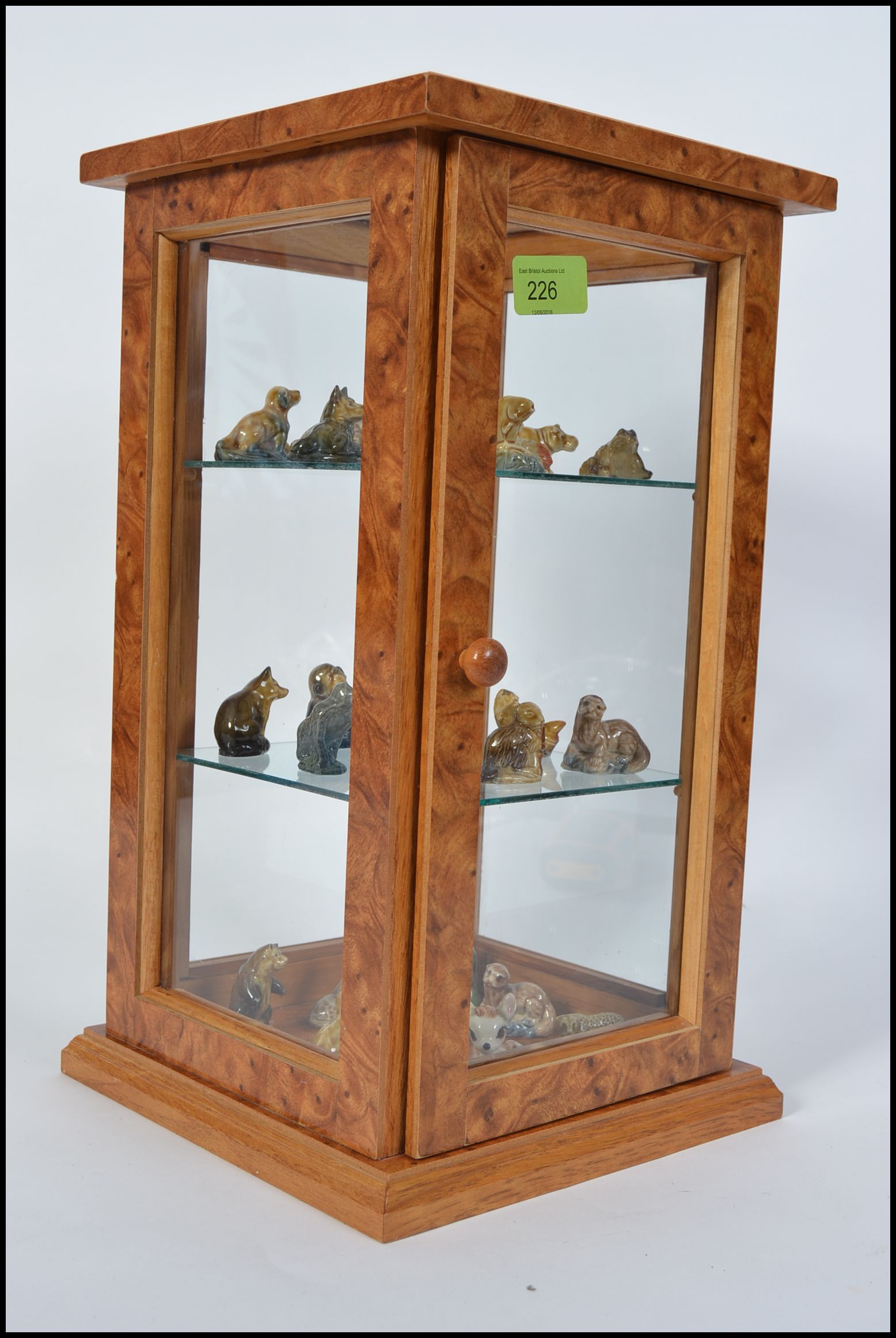 A collection of various ceramic Wade Whimsies complete with a small glazed upright display cabinet