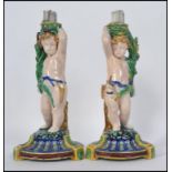 A pair of Minton Majolica figural candlesticks modelled as cherubs raised on naturalistic socle