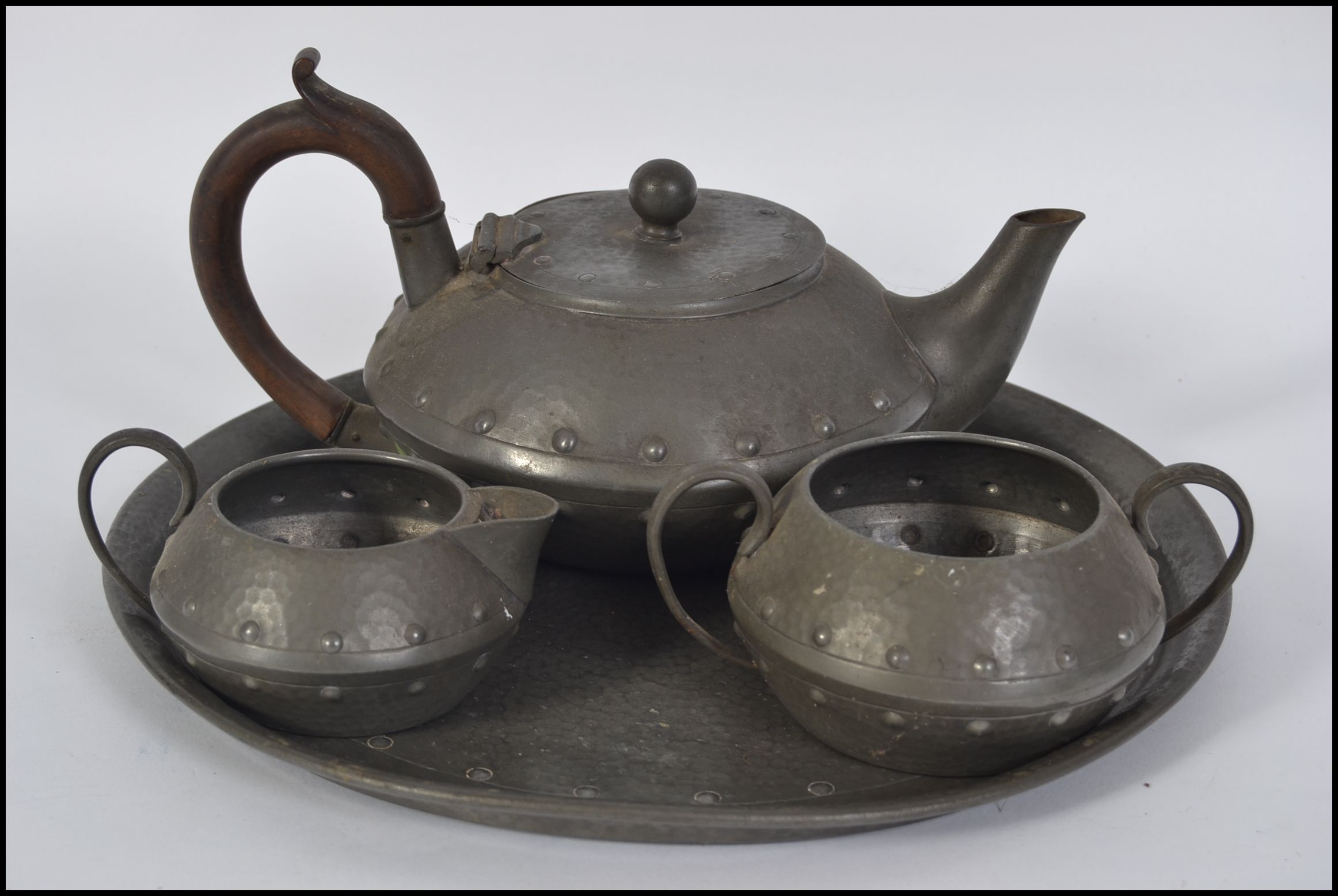 An Arts & Crafts pewter 4 piece tea service comprising teapot, sugar bowl, creamer and tray.