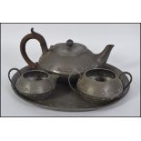 An Arts & Crafts pewter 4 piece tea service comprising teapot, sugar bowl, creamer and tray.