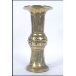 A Chinese brass gu vase of cylindrical form with geometric designs and symbols,