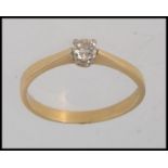 An 18ct gold ring set with central round cut solitaire diamond in a prong setting.