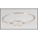 A silver contemporary ladies twin heart bangle / bracelet stamped 925.