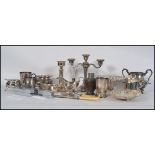 A collection of silver plated items to include teapot, creamer, candlesticks, beakers, tankards,