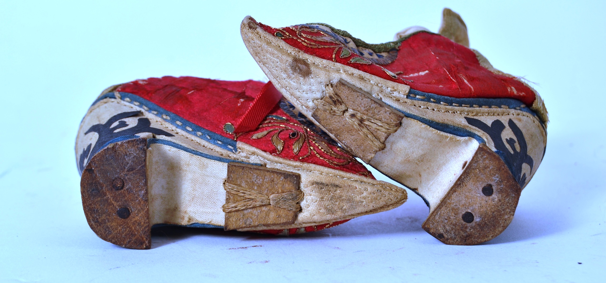 A pair of Chinese red silk and embroidered shoes with laces being handstitched, - Image 4 of 4