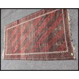 An early 20th century handwoven Persian rug with red ground - black wave design to centre and wavey