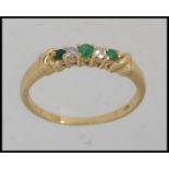 A gold ring testing 18ct set with alternating emeralds and diamonds in a prong setting. Size O.5.