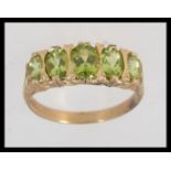 A 9ct gold peridot inset 5 stone ring of graduating sizes set on a decorative shank.