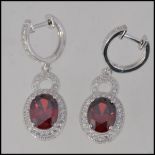 A pair of ladies silver Cz and garnet adorned drop earrings,