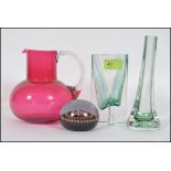 A collection of glass items to include a handmade cranberry jug, paper weight and glass vases,