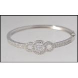 A ladies contemporary silver bangle adorned with cz stones having ribbon / daisy head centre