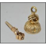 An unmarked fob watch winding key tests 15ct gold with pierced decoration together with a white