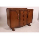 A 1930's Art Deco oak sideboard having a central bank of drawers with cupboards either side.