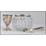 A silver hallmarked egg cup together with a pair of silver sugar tongs and a cut glass and silver