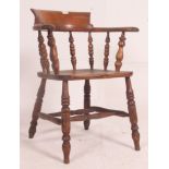 A Victorian beech and elm smokers bow windsor armchair being raised on turned legs united by