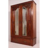 An Edwardian mahogany arts and crafts double wardrobe having plinth base with drawer and double