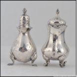 A silver hallmarked cruet set ( non matching ) of bulbous body each raised on splayed legs 70.