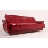 A fabulous retro 1950's red vinyl sofa settee day bed raised on tapering suports.