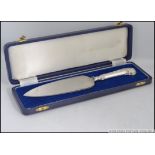 A cased silver hallmarked cake knife / server complete in the blue presentation case.