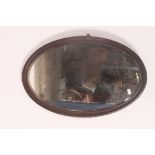 A large 19th century oval wall hanging mahogany framed mirror, having a bevel edged mirror panel.