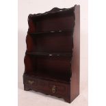 An antique style mahogany waterfall bookcase having shaped sides and graduating shelves with