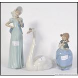 A boxed Lladro swan figurine together with 2 boxed Nao figurines, one of a child, the other a dame.
