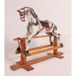 A 20th century rocking horse of wooden construction with painted dapple grey finish having glider