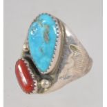 A vintage sterling silver ring set with a turquoise and coral in a brutalist setting with etched