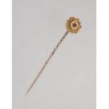 A Victorian 15ct gold stick pin with central ruby in a star cut setting surrounded by filigree,