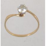 A hallmarked 9ct gold ring with a large prong set clear stone approx 25pts on a cross over band.