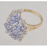 A hallmarked 9ct white gold ring set with tanzanite and diamonds in a prong set foliate cluster.