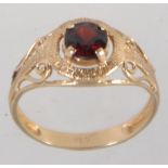 A hallmarked 9ct gold ring set with a single large round cut garnet in a prong setting with pierced