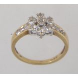 A 9ct gold and diamond ring with central diamond cluster and channel set diamond shoulders.