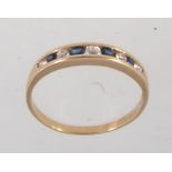 A hallmarked 9ct gold ring with channel set clear and blue stones. Import marks for London. Size P.