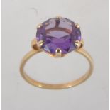 A 9ct gold dress ring set with a large round cut amethyst approx 5cts with hoop shoulders.