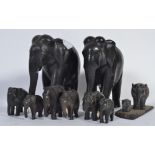 A group of carved ebony elephants of various sources with bone inlaid features