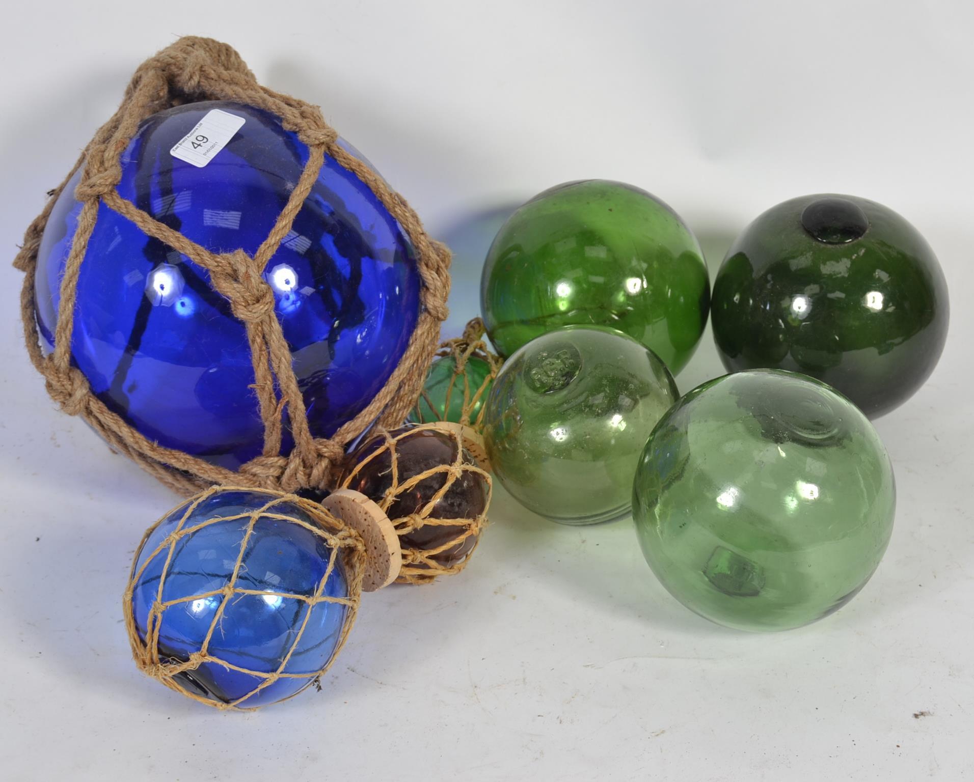 A good group of 7 20th Century coloured glass fishing floats some string bound of varying sizes
