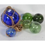 A good group of 7 20th Century coloured glass fishing floats some string bound of varying sizes