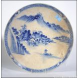 A large 19th century Kang-Xi Chinese blue and white wall charger with scenes of fishing boat,