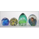 a collection of four glass paperweights