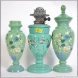 A late 19th century hand painted oil lamp with two matching vases each with hand painted floral