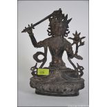 An early bronze Chinese figurine of a robed deity seated with sword and raised over socle plinth