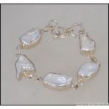 A contemporary silver and baroque pearl bracelet with bar and hoop mount. Marked 925.