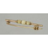 A early 20th century 9ct gold bar brooch with ivory ball styling with clip c clasp. Measures 3.3cms.