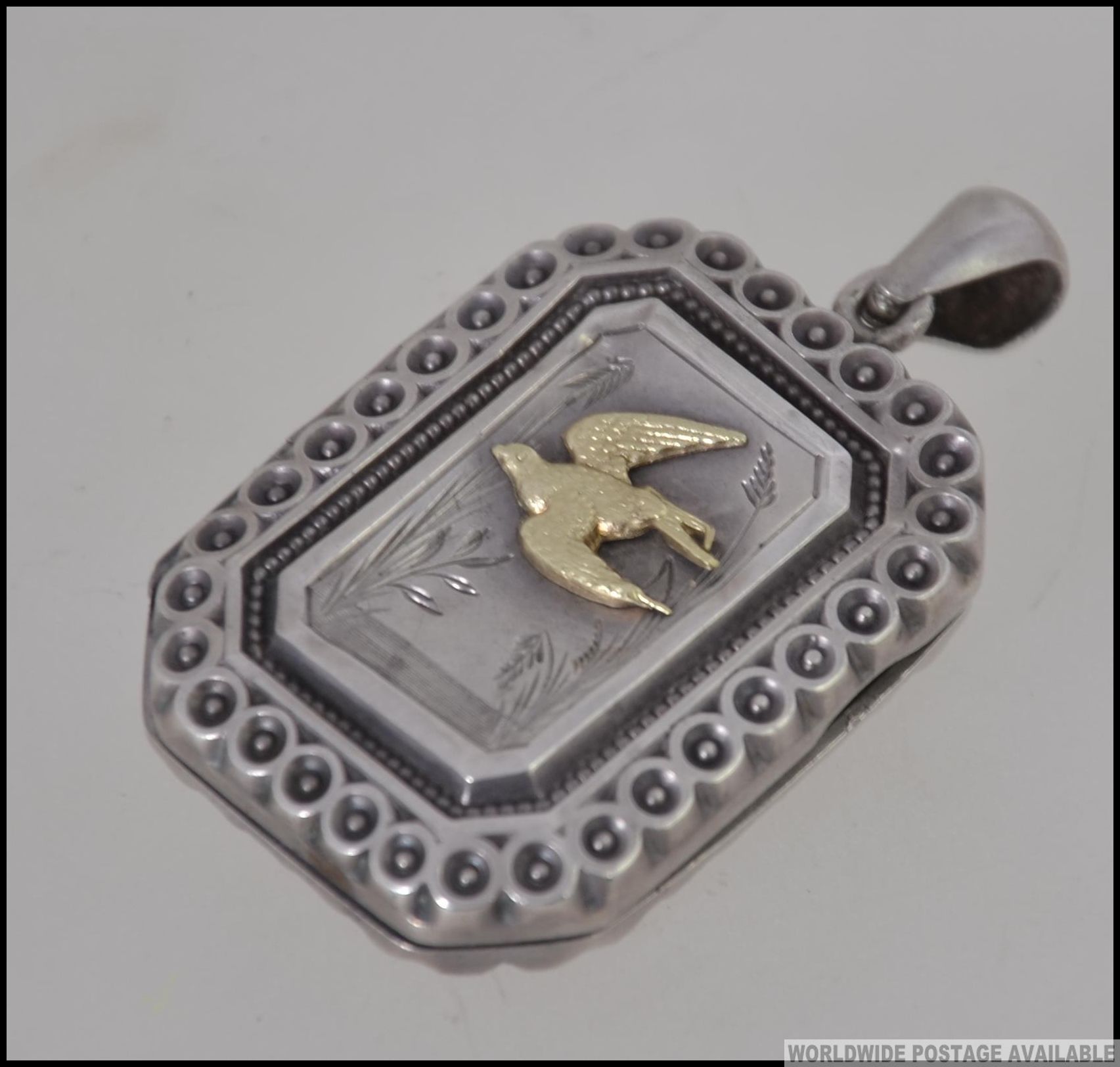 A Victorian silver locket of rectangular form with gilded bird being hallmarked for 1905,